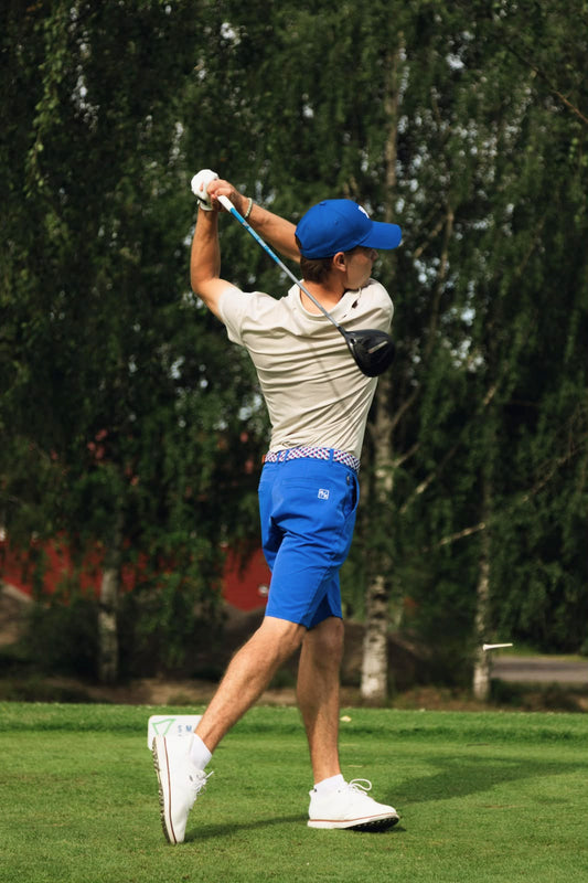 Golfer in electric blue golf shorts, cap and multicolored belt